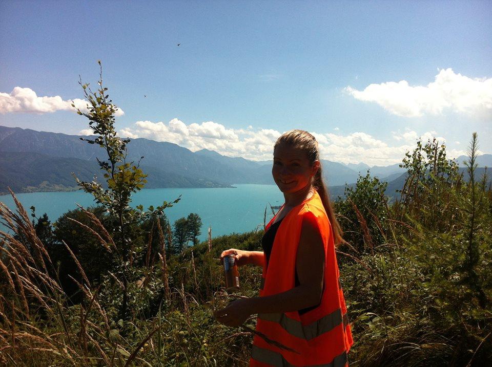 Claire Ries in einer orangen Warnweste auf einer Anhöhe nahe des Attersees