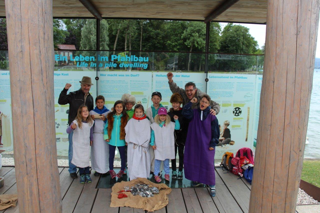 Eine Kindergruppe mit Betreuern steht im Pfahlbau-Pavillon