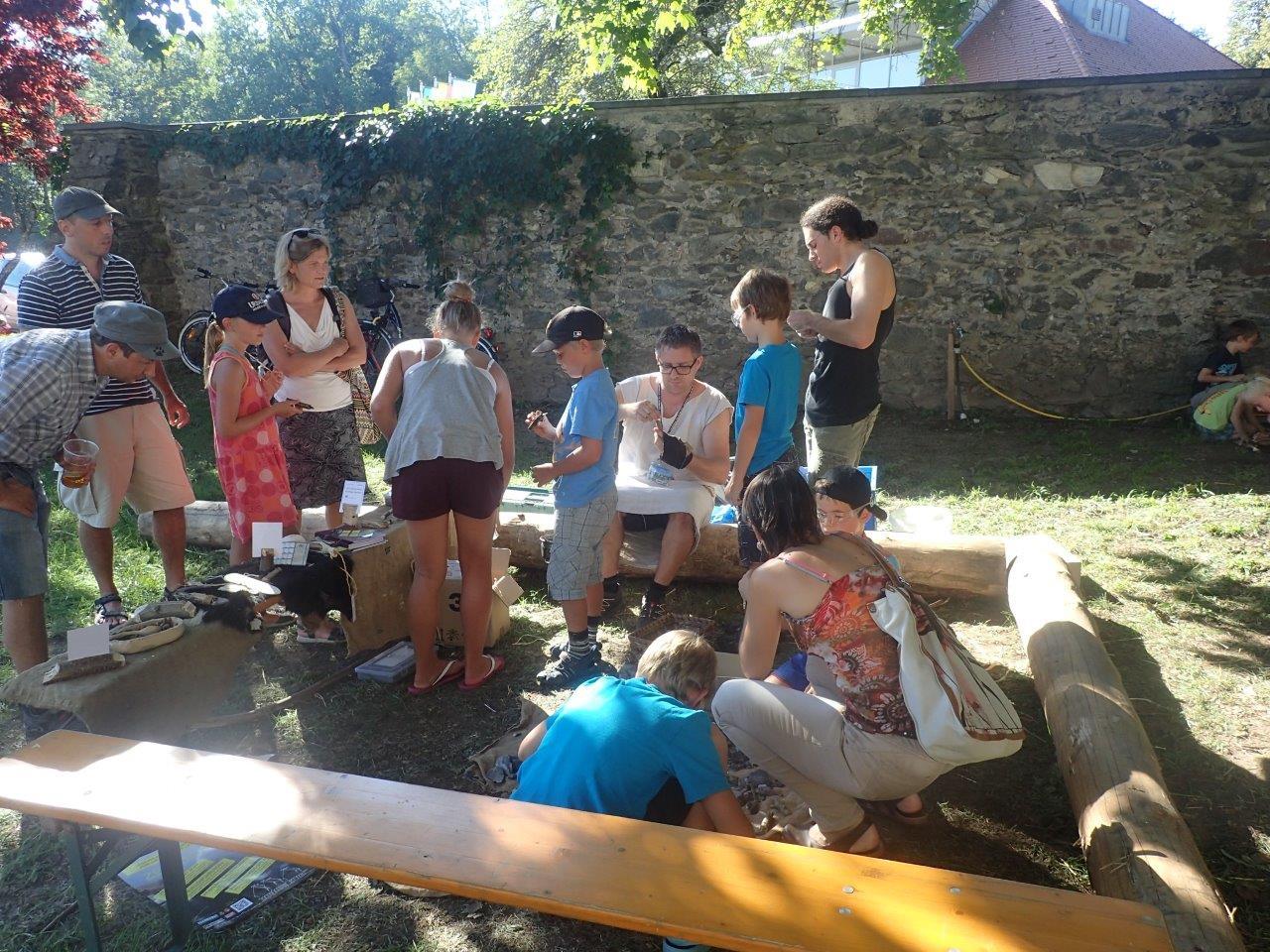Eine Kindergruppe beim Welterbefest in Keutschach vor einer Mauer, bei einer Mitmachstation