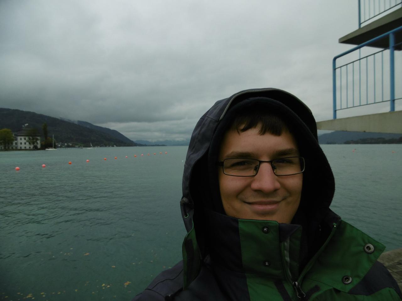 Florian Ostrowski in Regenjacke vor dem See 