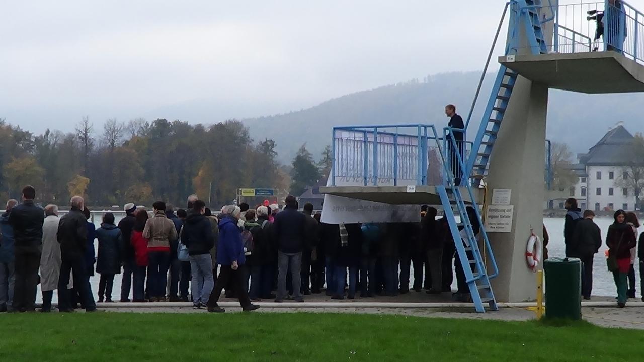 Eine große Menschengruppe drängt sich um den Sprungturm in Seewalchen