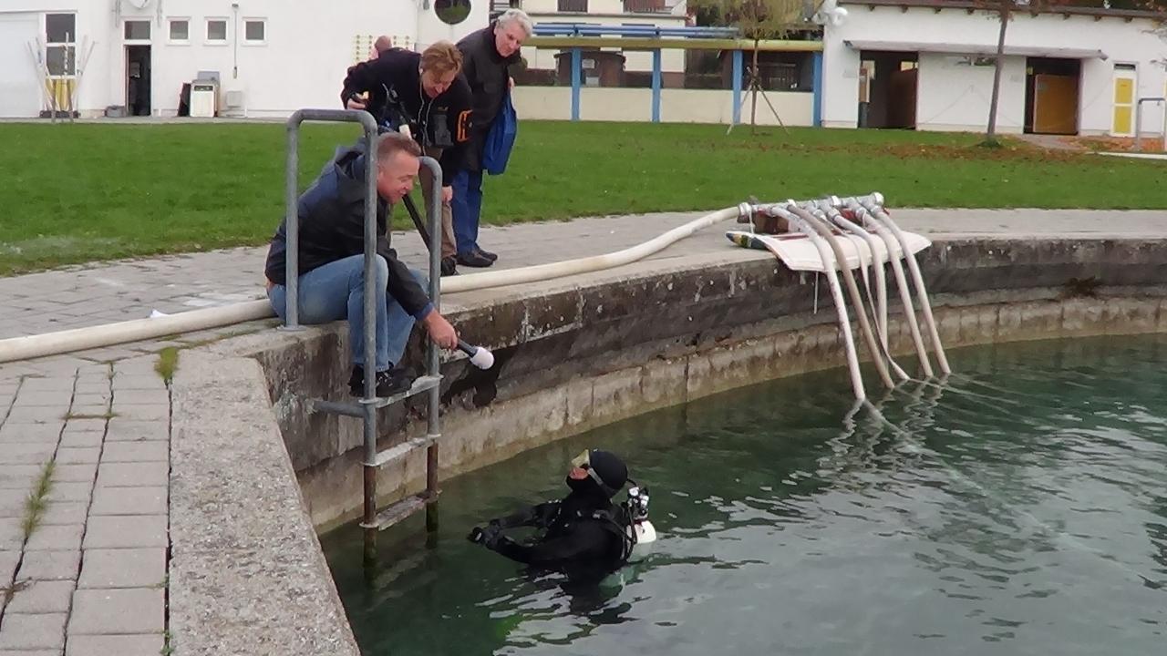 Helena im Tauchanzug steht bis zur Brust im Wasser udn wird vom Ufer von 2 Personen interviewt