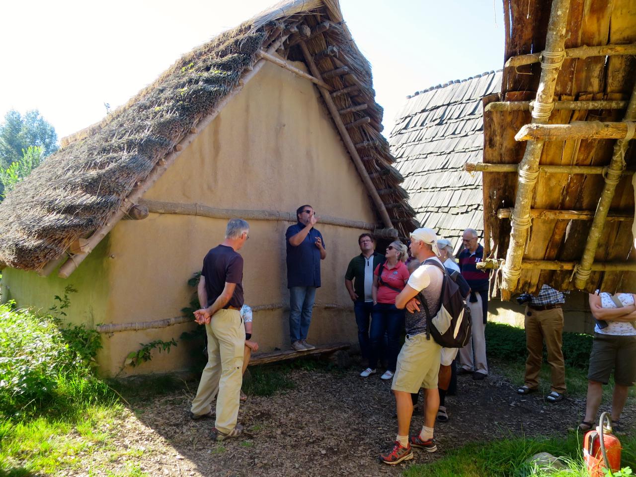Zwischen Hausrekonstruktionen steht eine Besuchergruppe im Federseemuseum