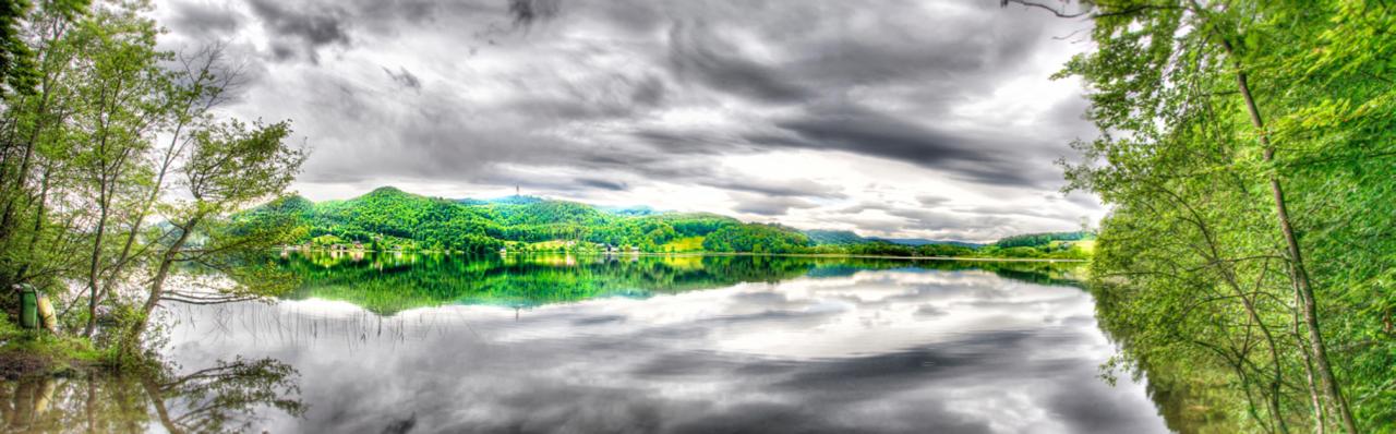 Panoramabild vom Keutschacher See in Grau- und Grüntönen