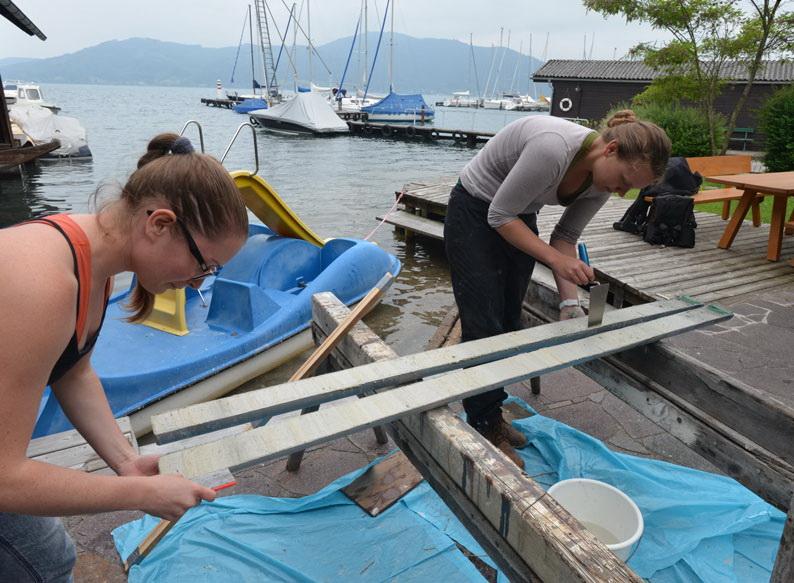 2 Frauen stehen gebeugt über der Kernprobe auf einem Steg im Yachthafen