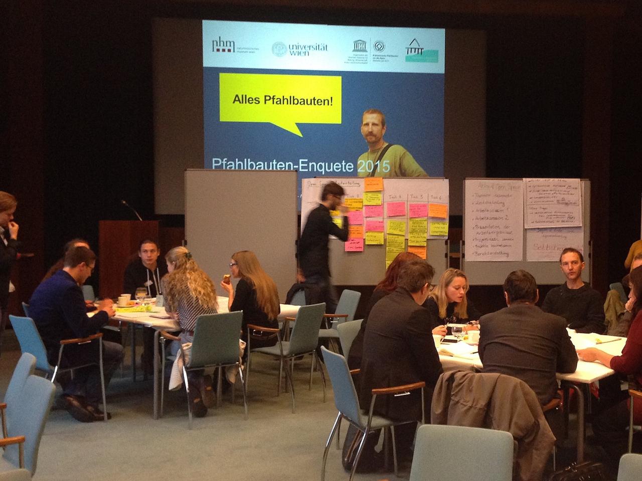 Mehrere Arbeitsgruppen sitzen an getrennten Tischen und Visionboards