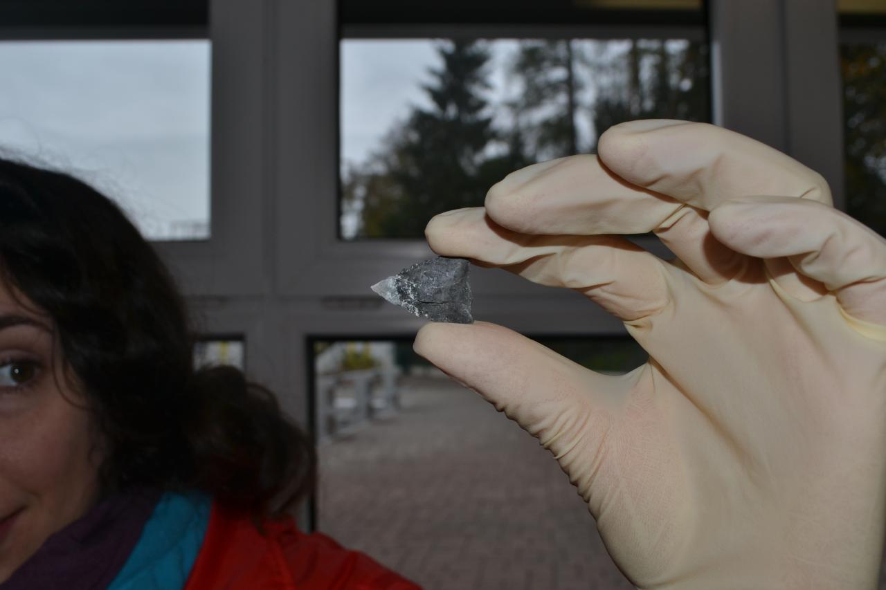 Eine steinerne Pfeilspitze wird von Susanne in die Kamera gehalten