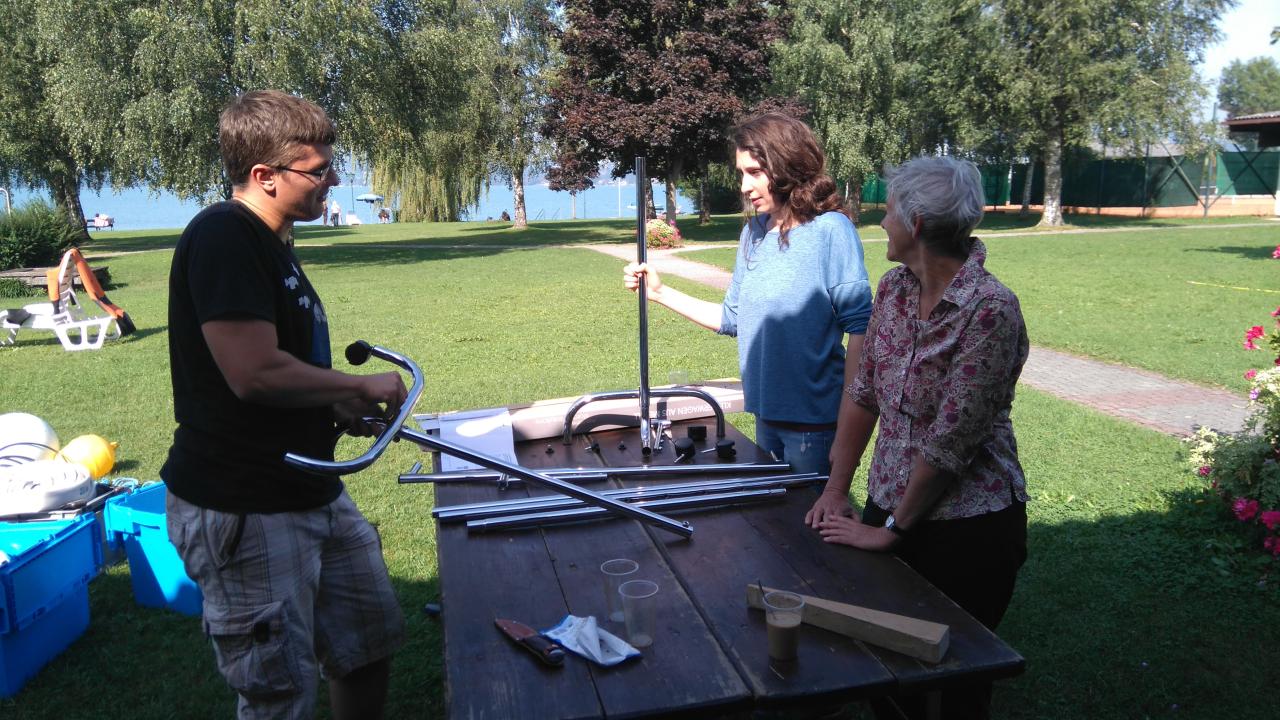 3 Personen stehen an einem Tisch, um ein Regal zusammenzubauen