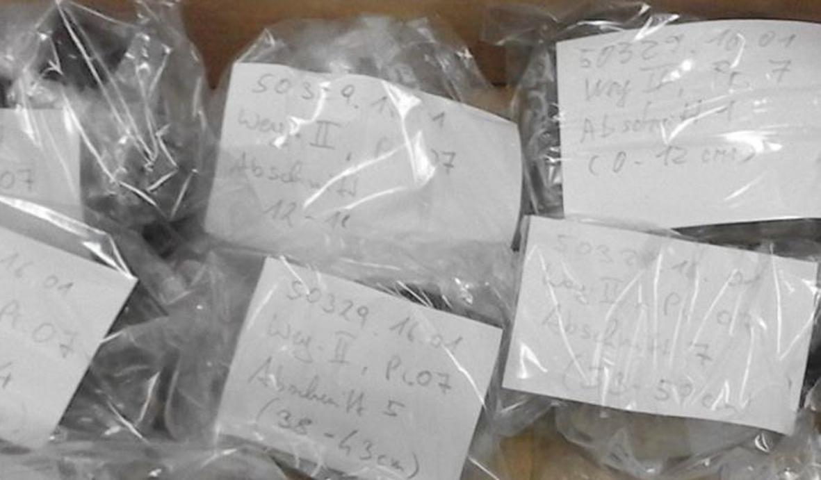 Proben in Plastikbeuteln mit handschriftlichen Beschriftungen auf weißem Papier