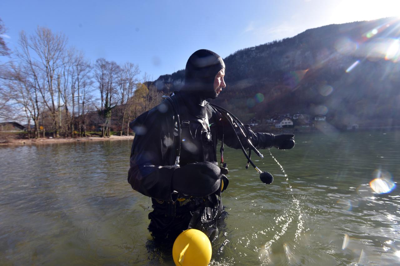 Ein Taucher steht bis zu den Hüften im Wasser und blickt auf den See