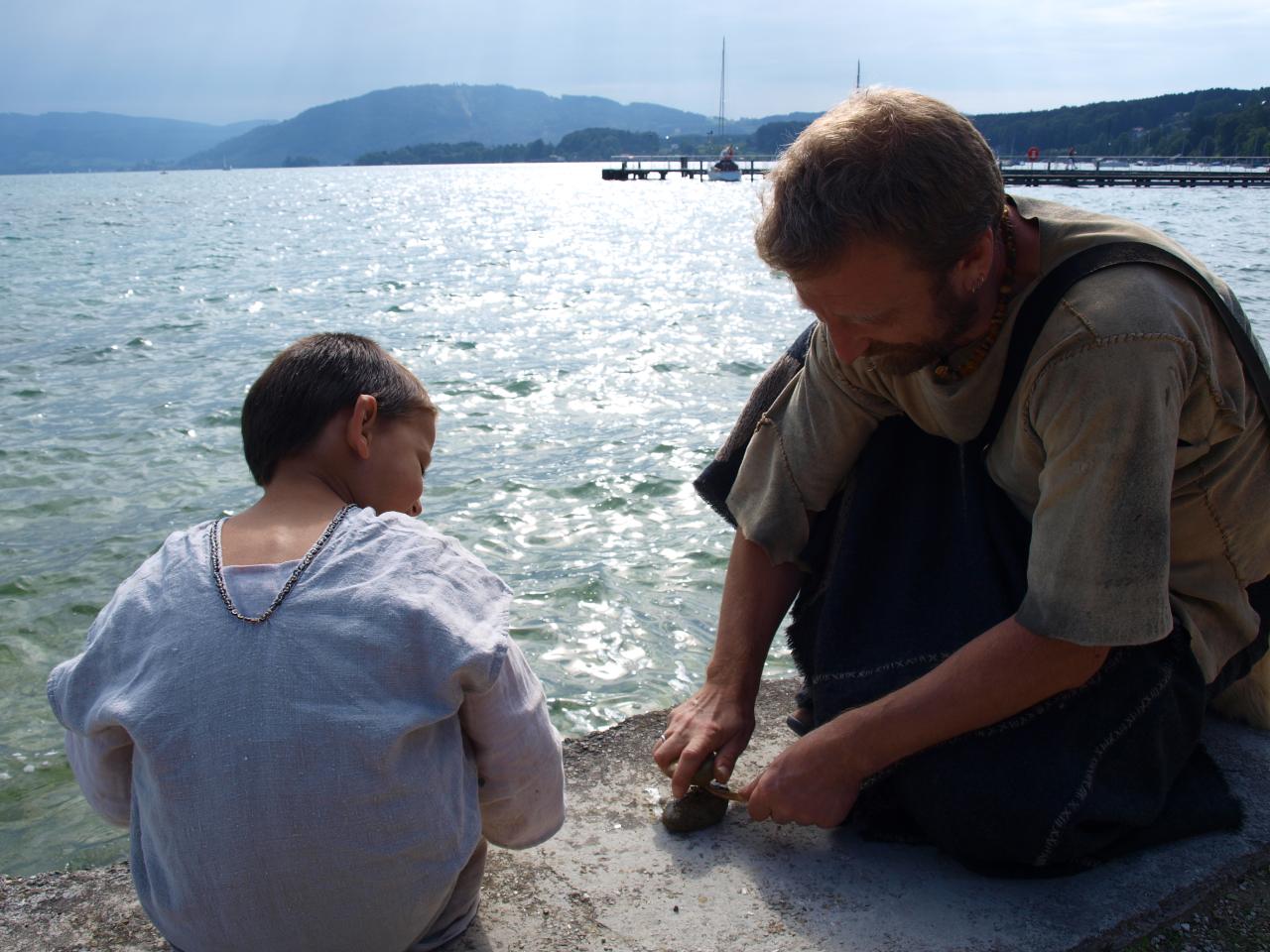 Ein Mann und ein Kind knien am Ufer des Attersees 