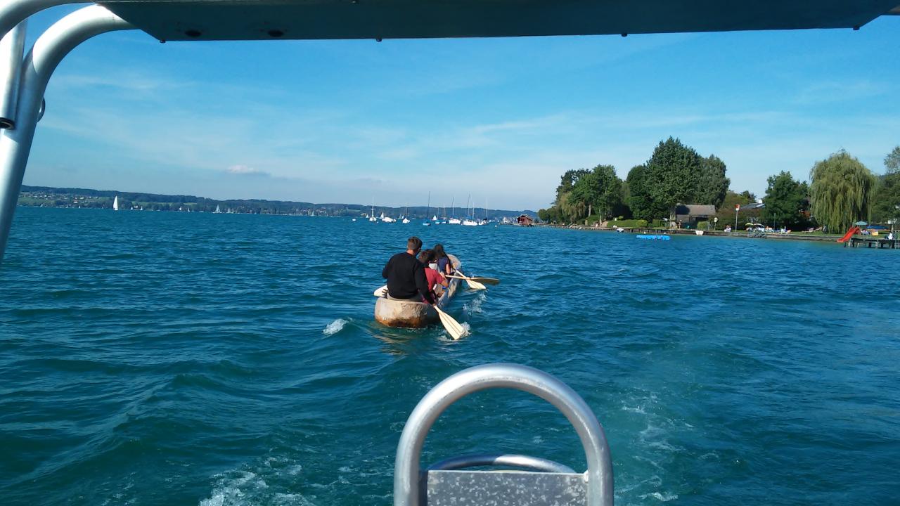Man sieht den Einbaum mit mehreren Personen an Bord