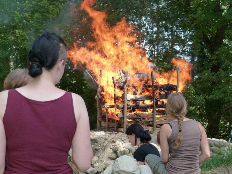 Ein Scheiterhaufen in Vollbrand wird von Student:Innen betrachtet
