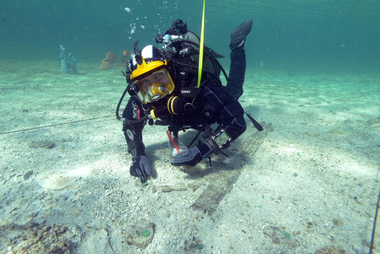 Forschungstaucher markiert Hölzer unter Wasser