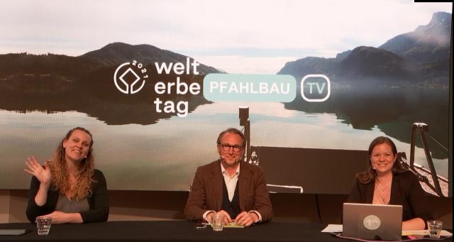 3 Personen sitzen in einem Fernsehstudio und blicken zur Kamera