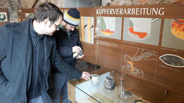 2 Personen betrachten eine Vitrine im Pfahlbaumuseum in Mondsee.