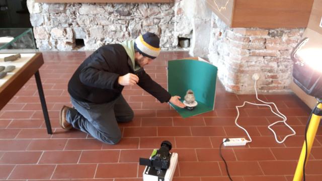 Eine am Boden knieende Person scannt den Krug im Museum in Mondsee.