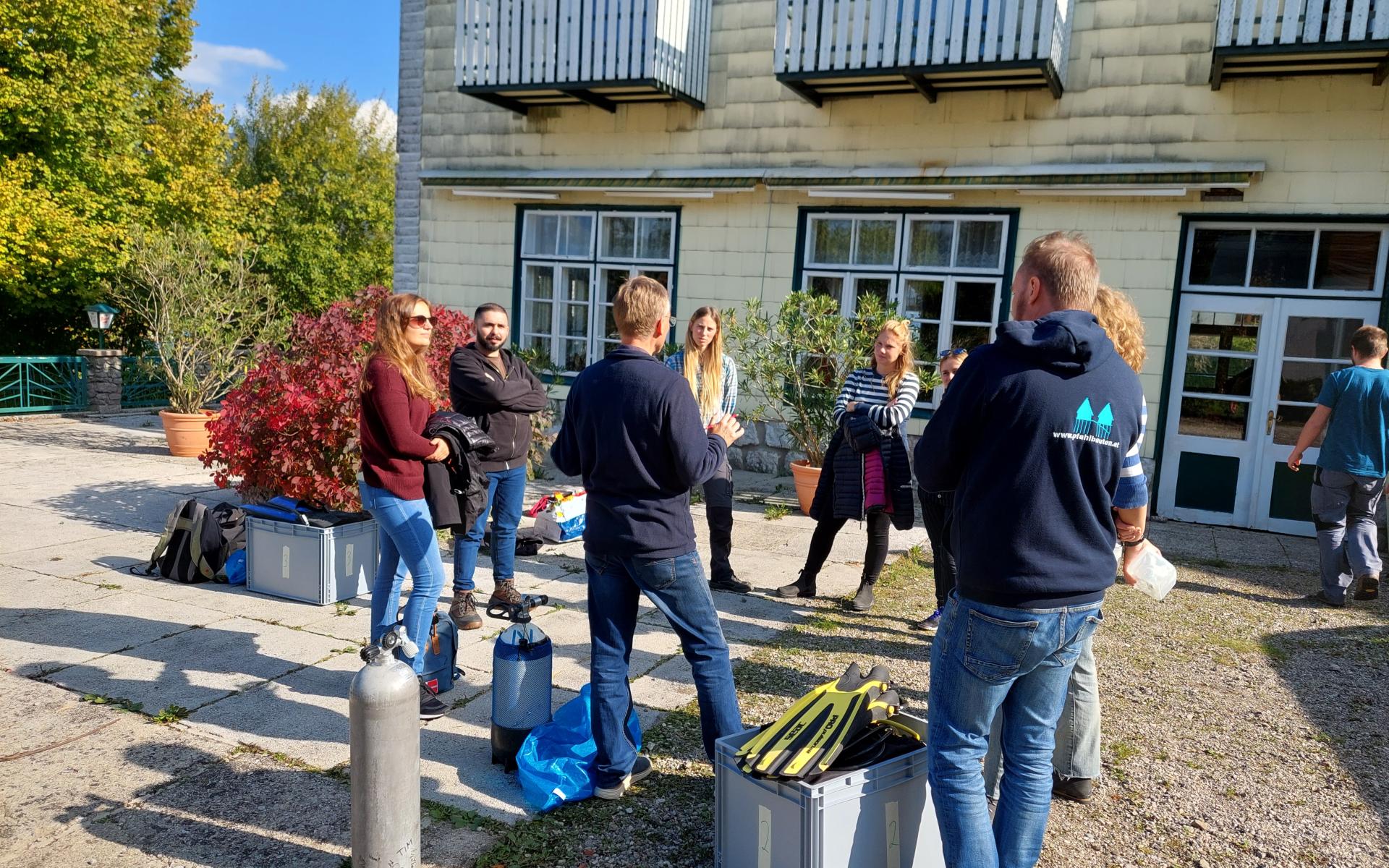 Eine Personengruppe steht vor einem Haus im Kreis