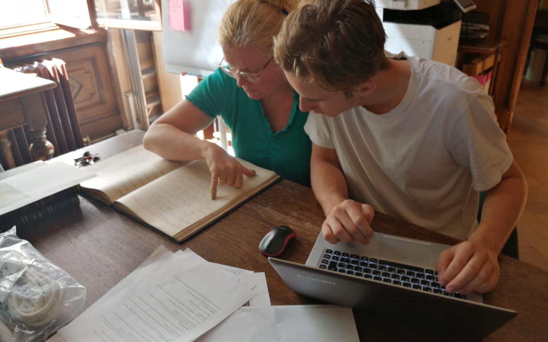 Karina Grömer und Michael Lonsing vor einem Laptop und einem Buch