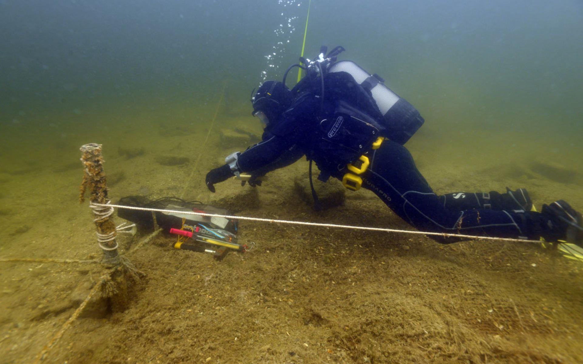 Ein Taucher, der unter Wasser entlang einer gespannten Schnur etwas misst