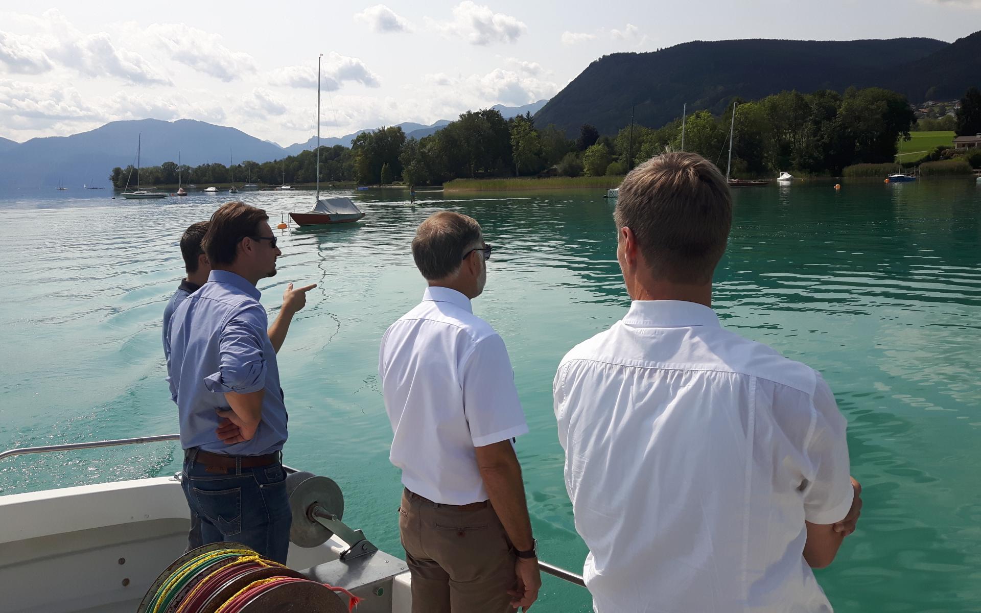 4 Personen stehen auf einem Boot und betrachten den See