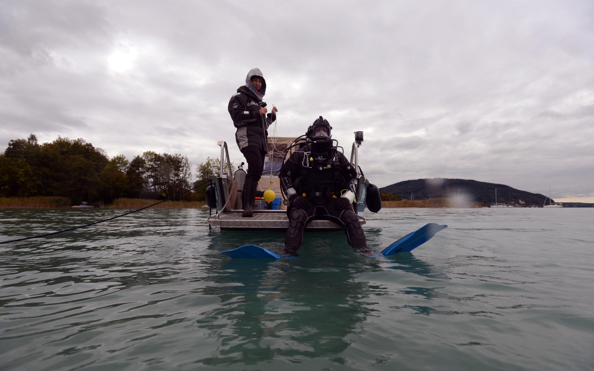 Ein Taucher kurz vor dem Einstieg aus dem Boot ins Wasser, eine 2. Person unterstützt ihn dabei