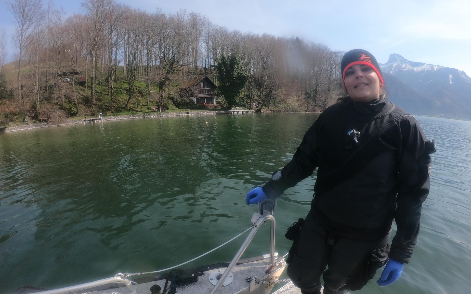 Eine Frau im Tauchanzug steht auf einem Boot, das im See schwimmt