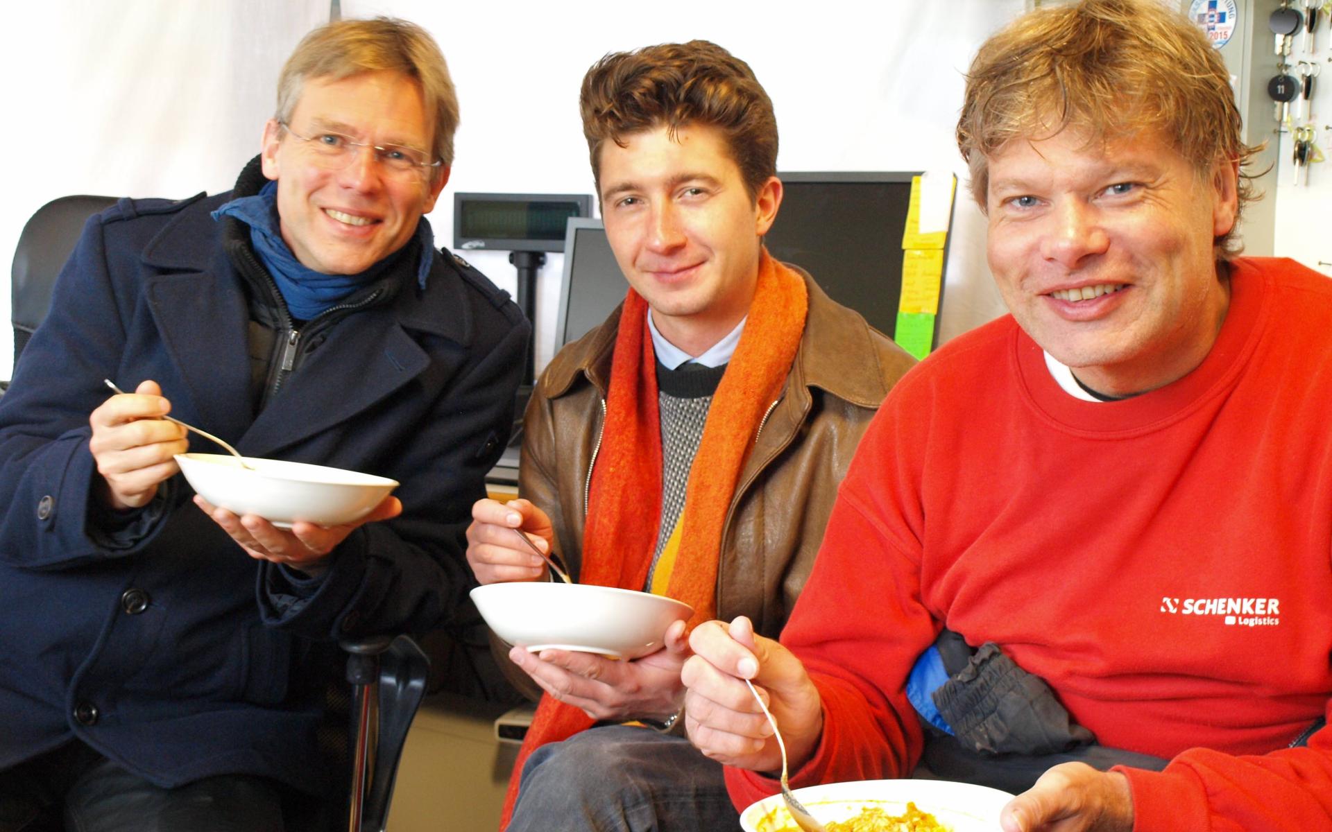 3 Personen sitzen mit Schüsselchen voll Curry im Büro