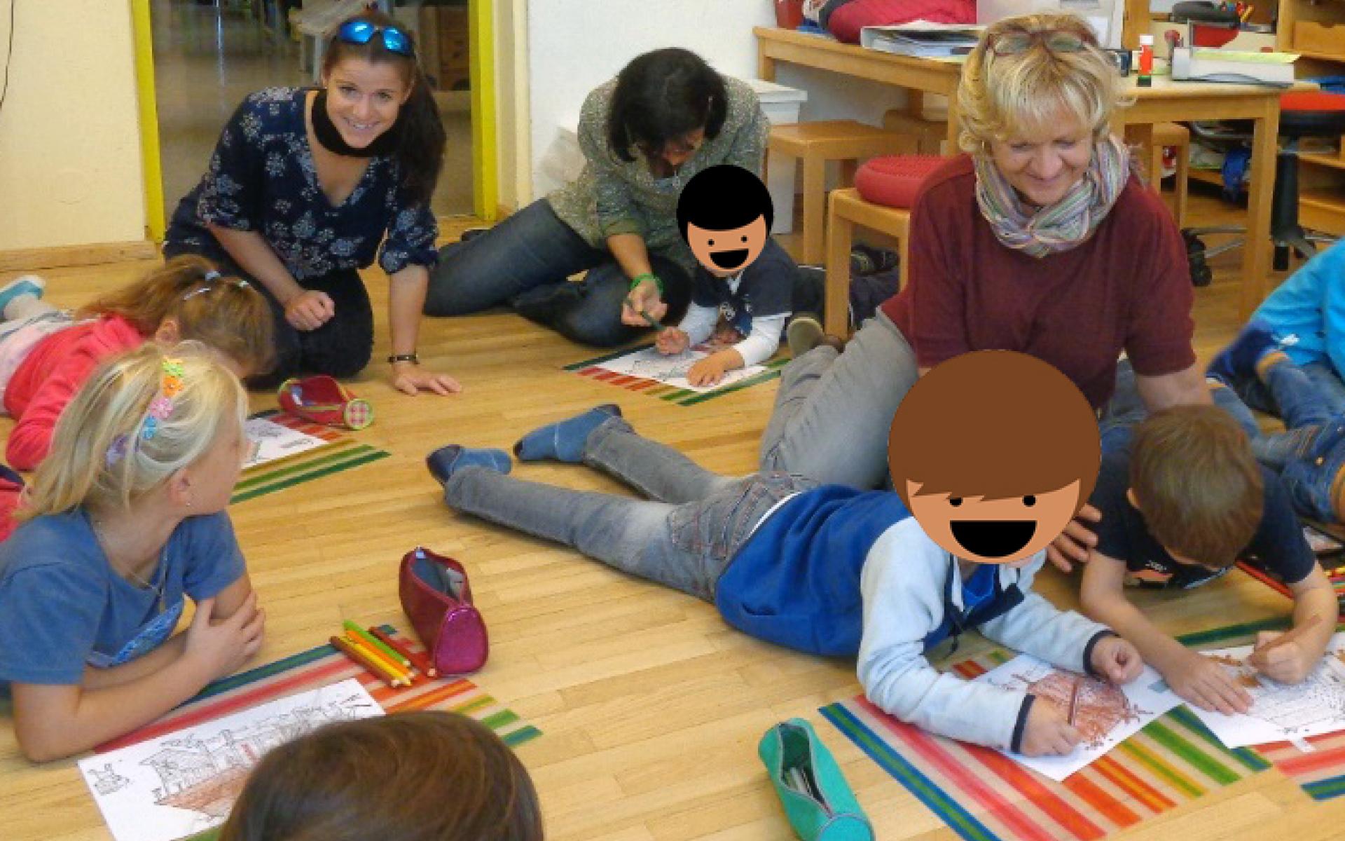 Eine Kindergruppe liegt malend auf dem Boden