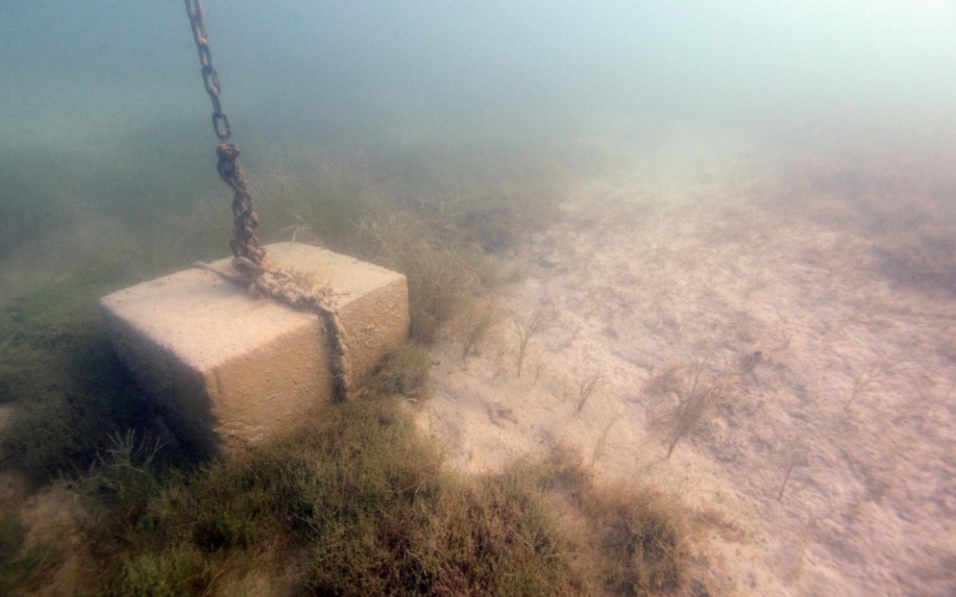 Ein angeketteter Zementblock am Seeboden auf dem befüllten Bojenkrater