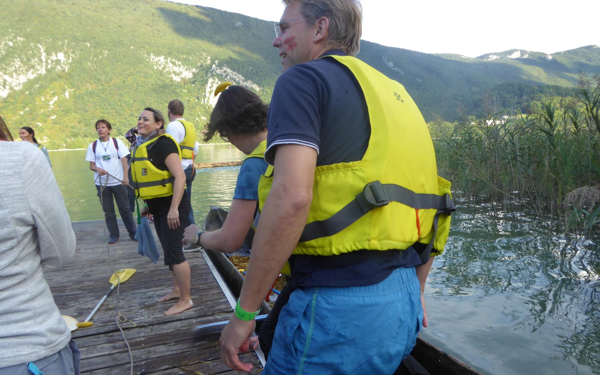 Mehrere Personen in gelben Schwimmwesten stehen auf einem Steg
