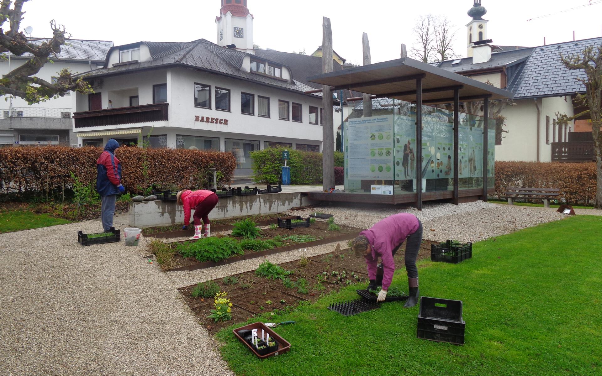 Mehrere Personen bei der Arbeit an den Beeten vor dem Pfahlbaupavillon