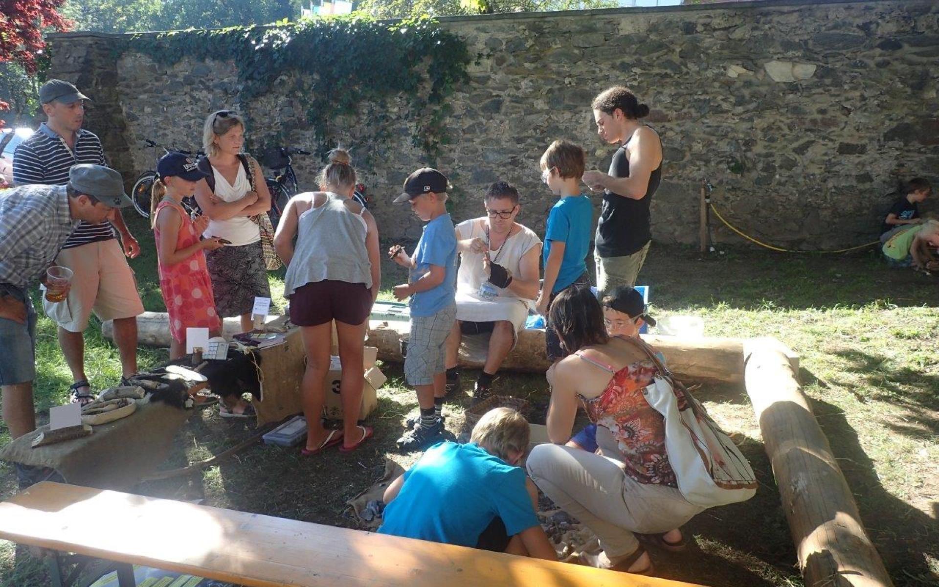 Eine Kindergruppe beim Welterbefest in Keutschach vor einer Mauer, bei einer Mitmachstation