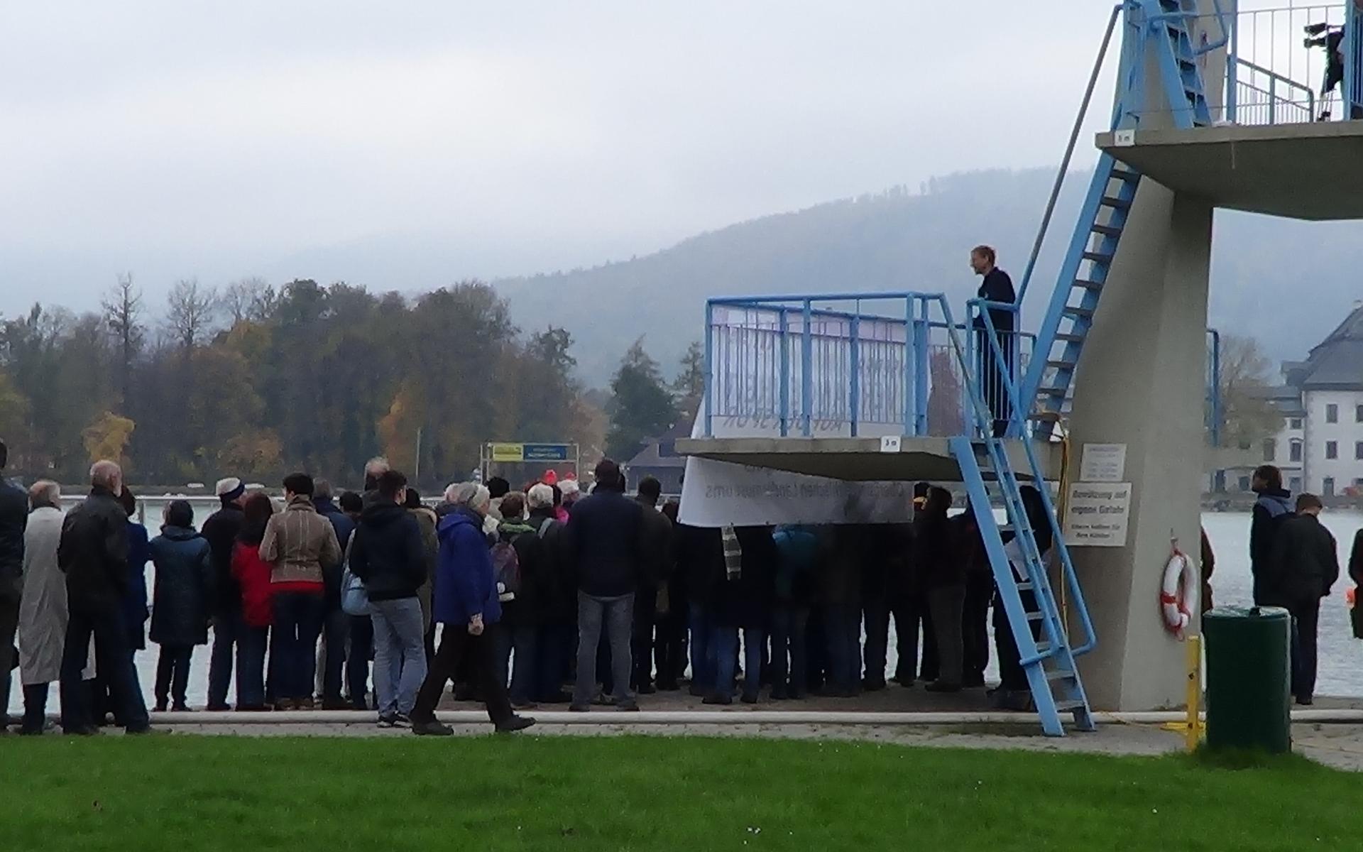 Eine große Menschengruppe drängt sich um den Sprungturm in Seewalchen