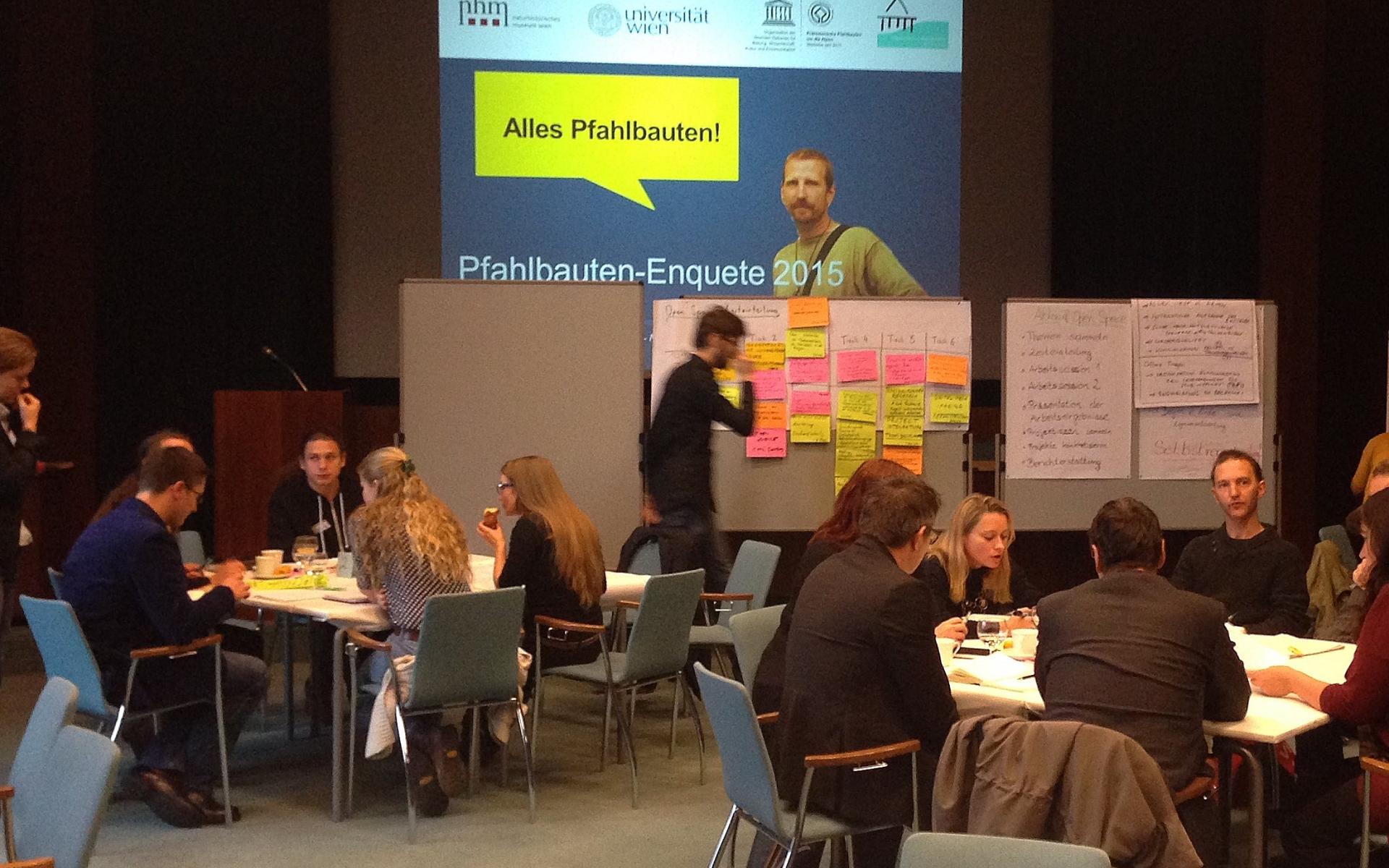 Mehrere Arbeitsgruppen sitzen an getrennten Tischen und Visionboards