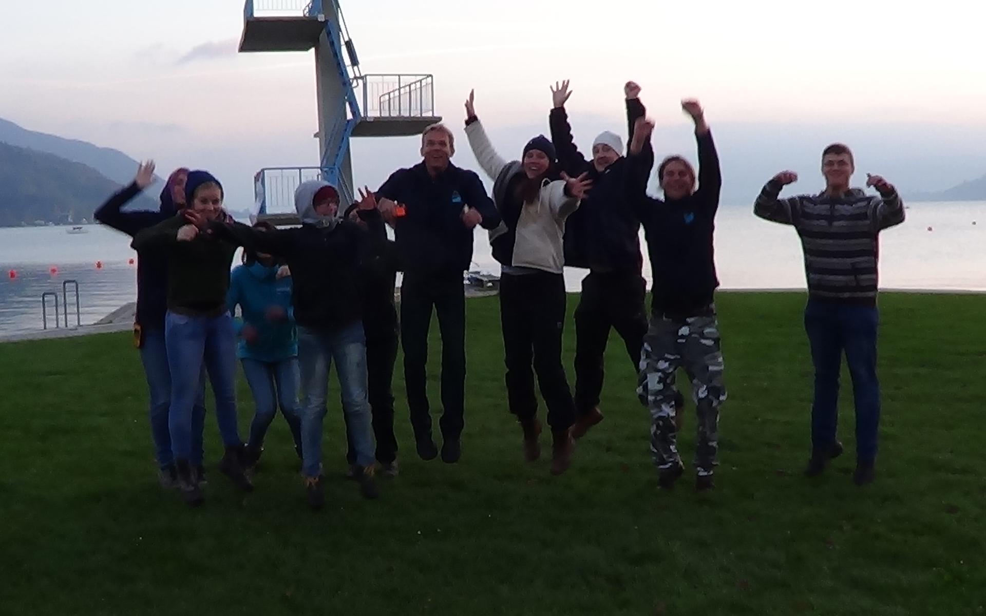 Eine Menschengruppe vor dem Sprungturm in Seewalchen wurde im Sprung fotografiert