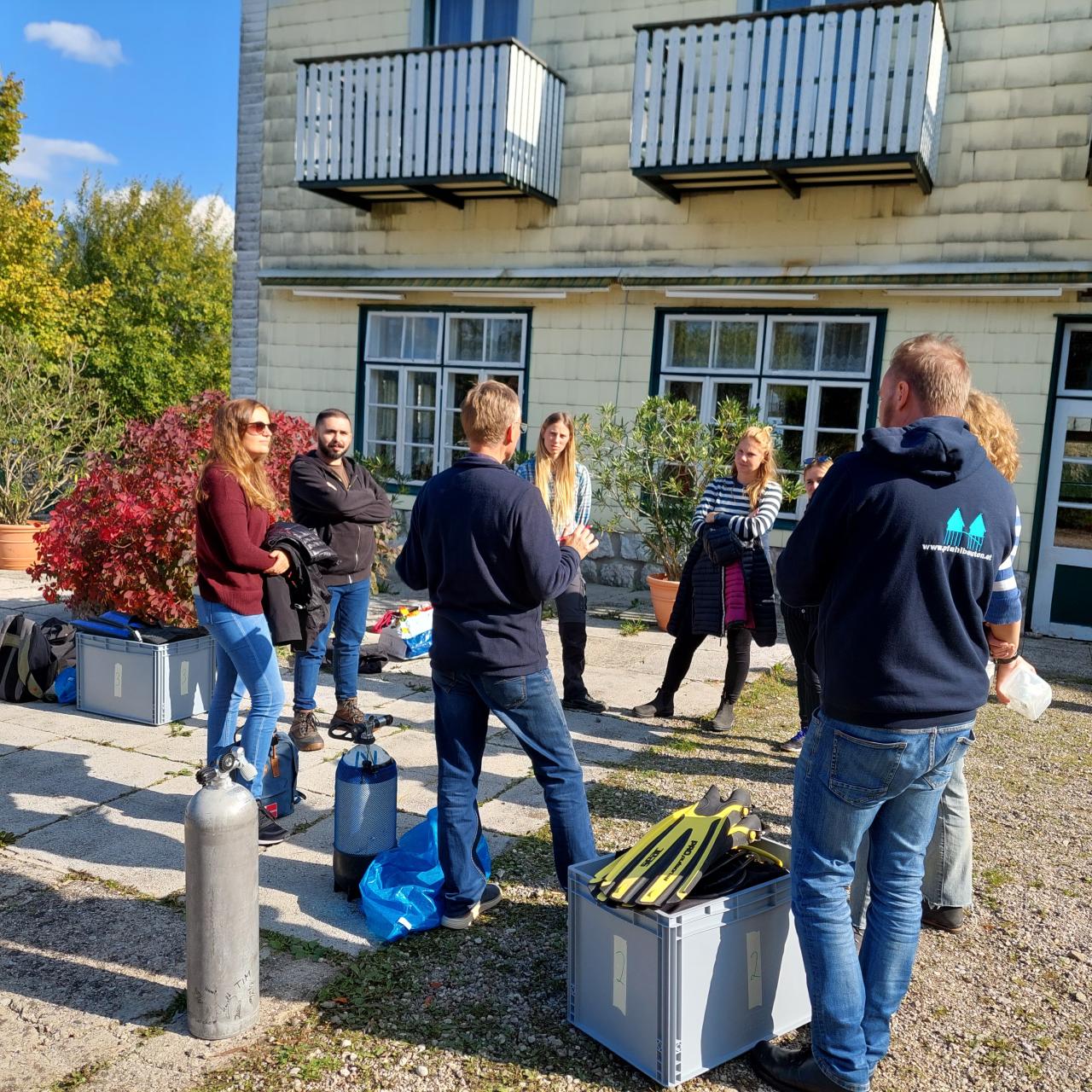 Eine Personengruppe steht vor einem Haus im Kreis