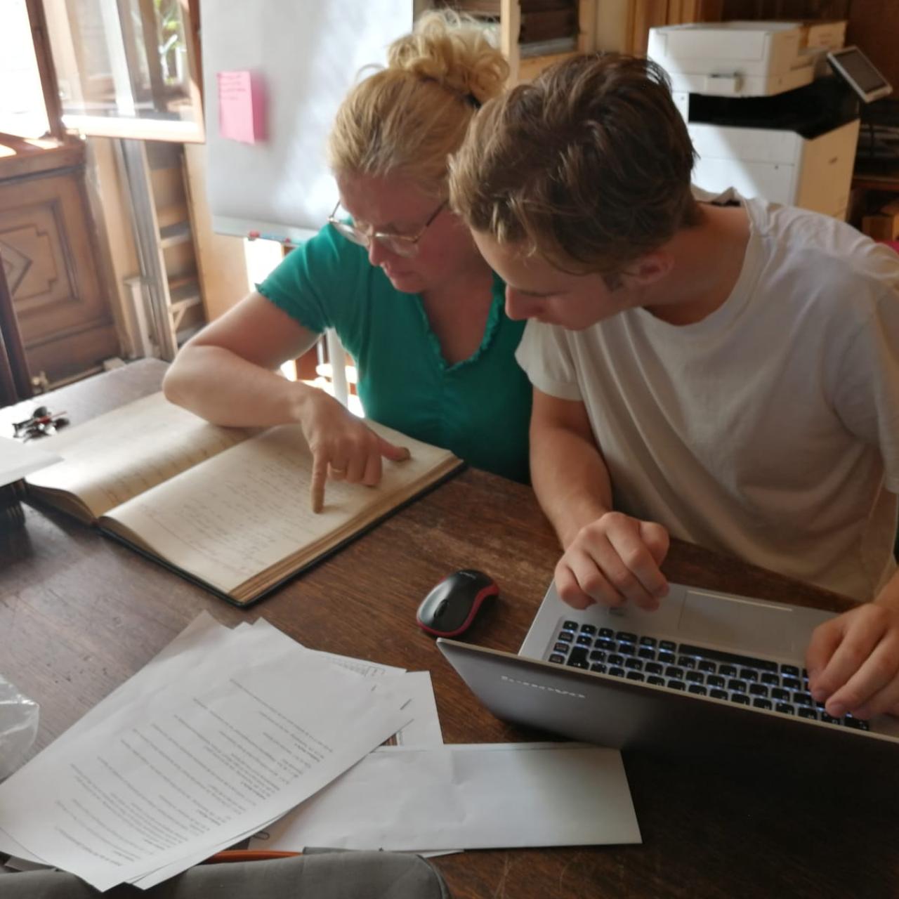 Karina Grömer und Michael Lonsing vor einem Laptop und einem Buch