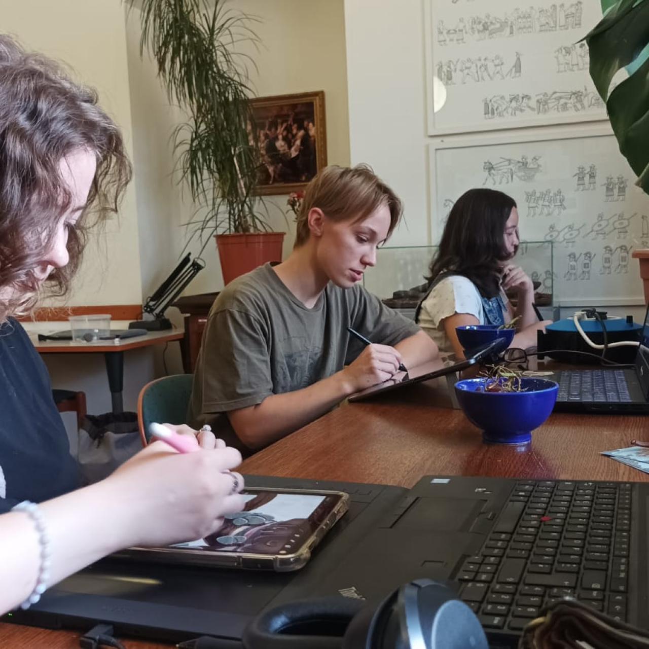 3 Personen sitzen an einem Schreibtisch und arbeiten an ihren Computern