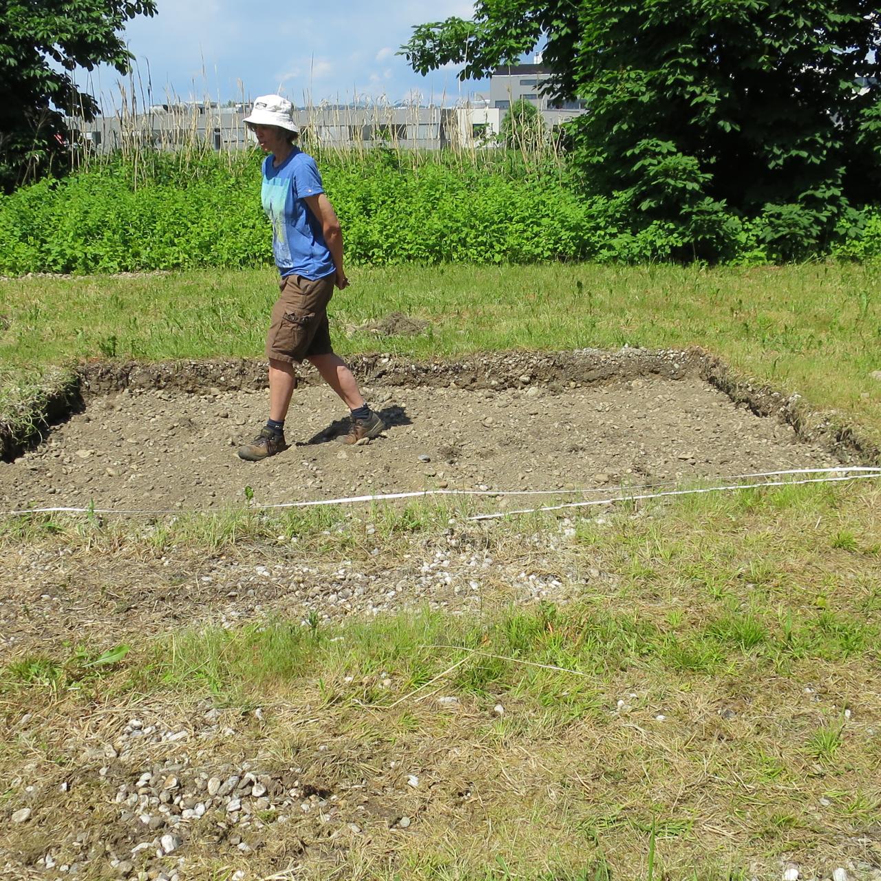 4 Personen stehen um eine flache Grube, die ein Gartenbeet werden soll