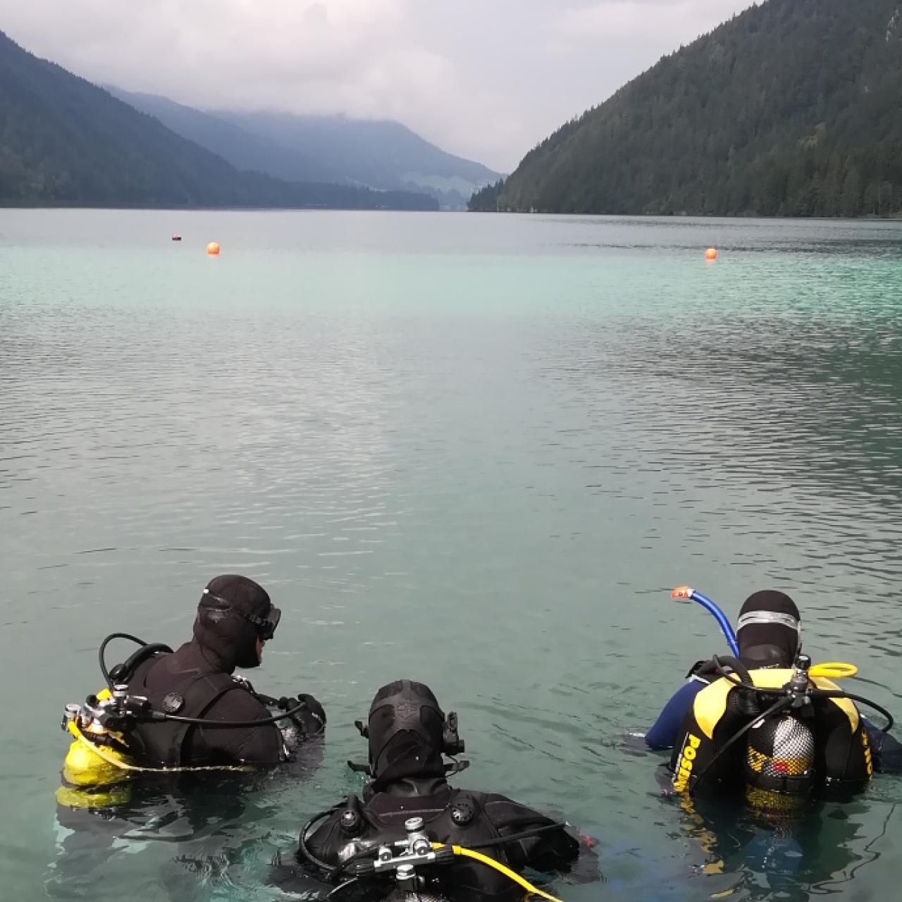 3 Taucher halb im Wasser des Weissensees