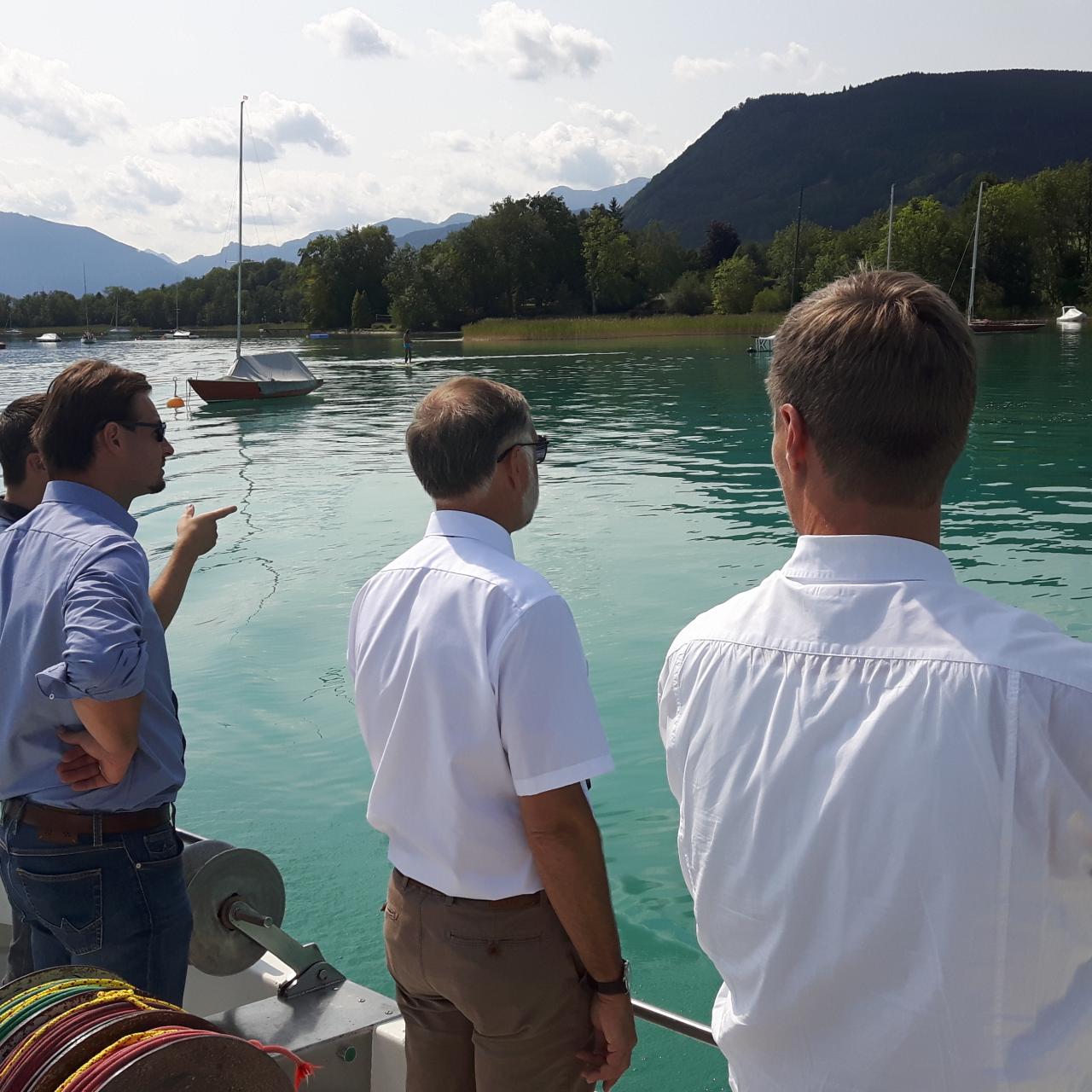 4 Personen stehen auf einem Boot und betrachten den See