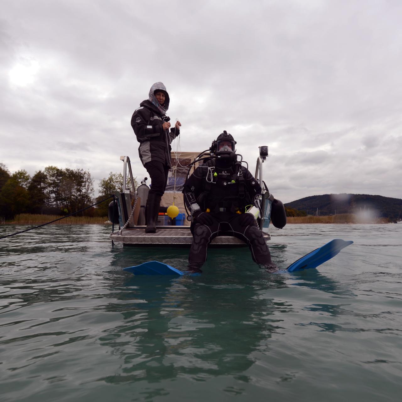Ein Taucher kurz vor dem Einstieg aus dem Boot ins Wasser, eine 2. Person unterstützt ihn dabei