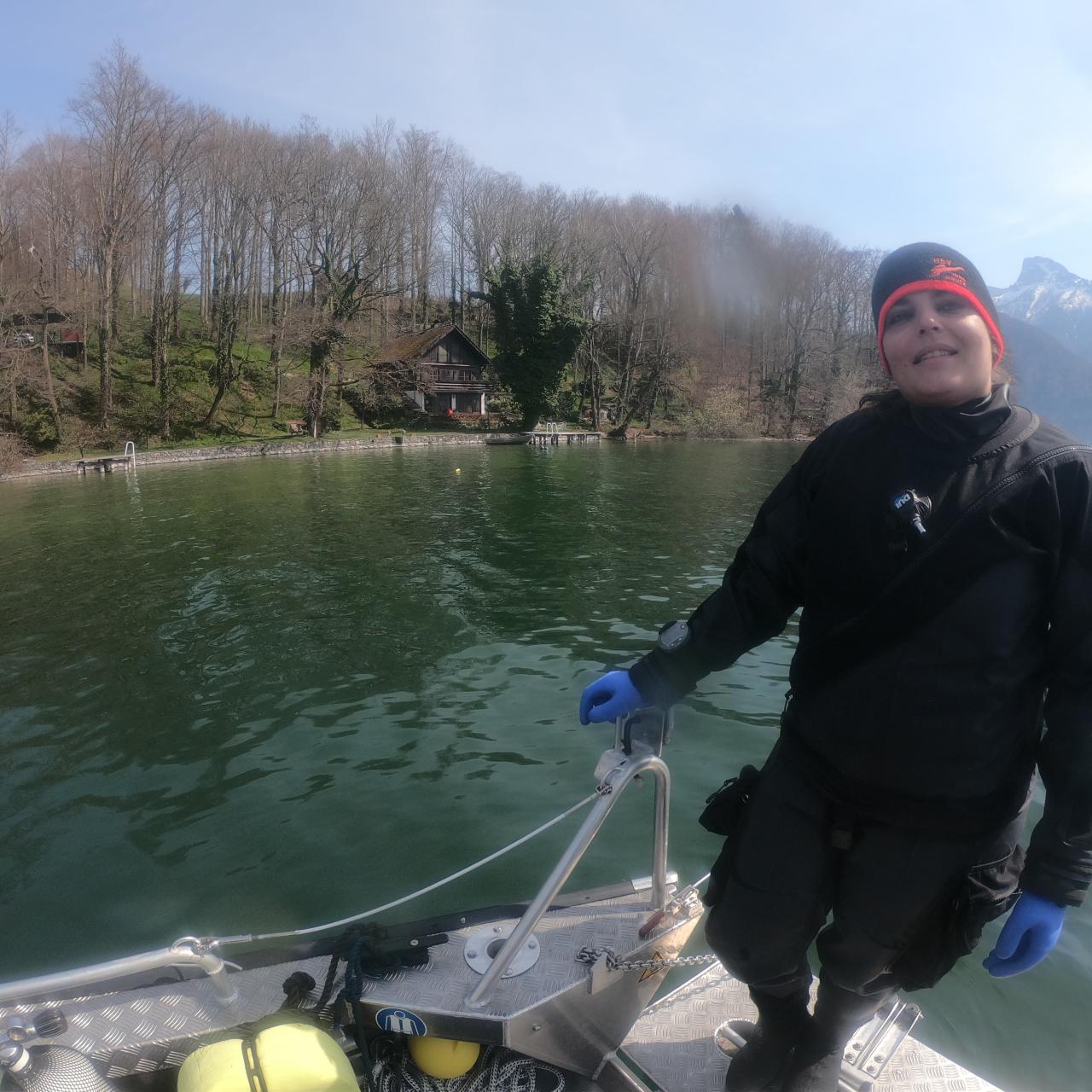 Eine Frau im Tauchanzug steht auf einem Boot, das im See schwimmt