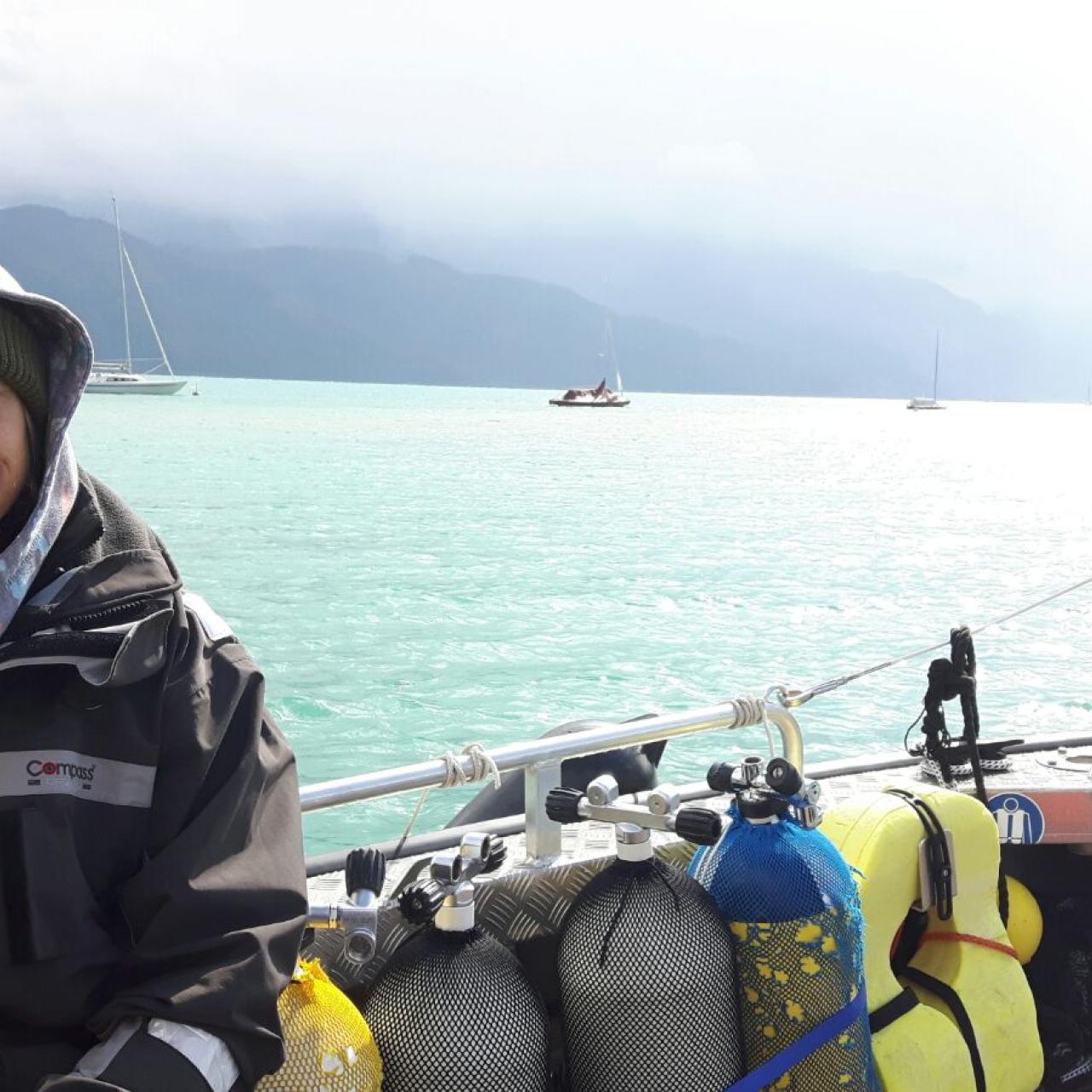 Esther sitzt neben den Tauchflaschen auf dem Boot
