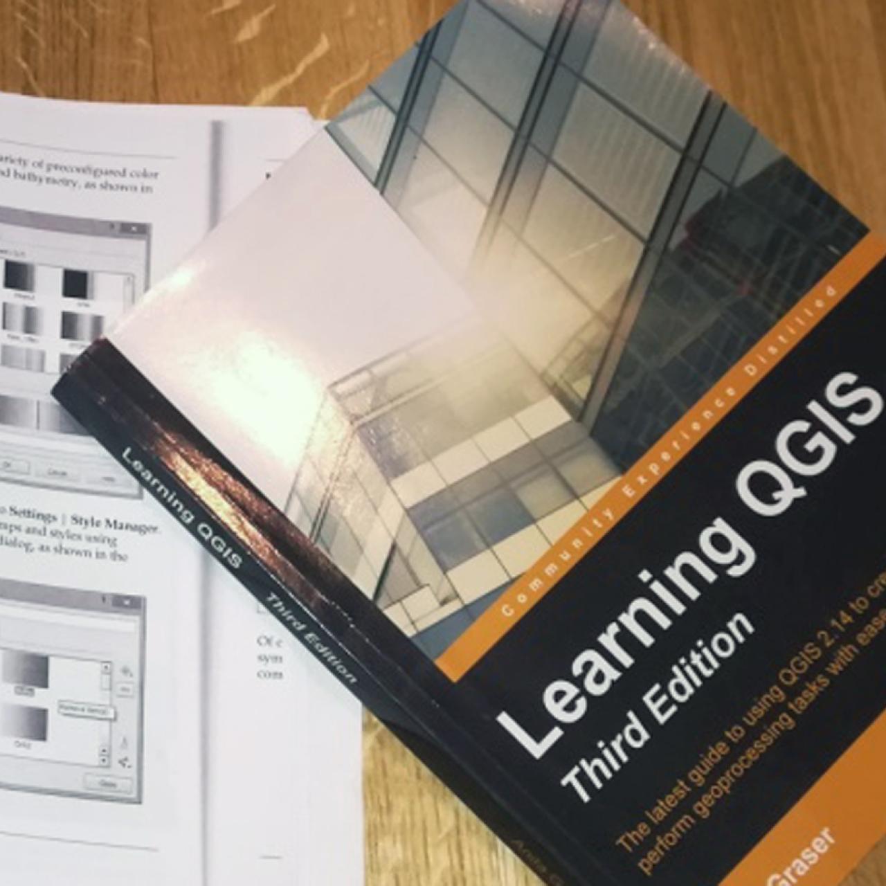 Ein Buch "Learning QGIS" auf einem weiteren geöffneten Buch