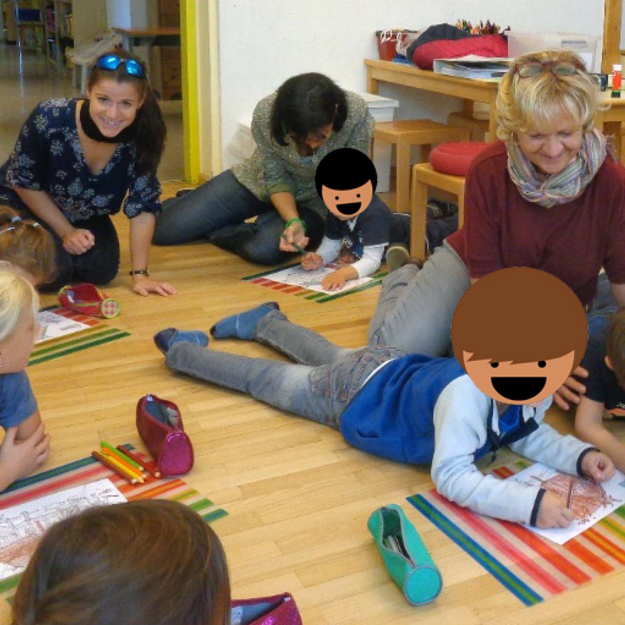 Eine Kindergruppe liegt malend auf dem Boden