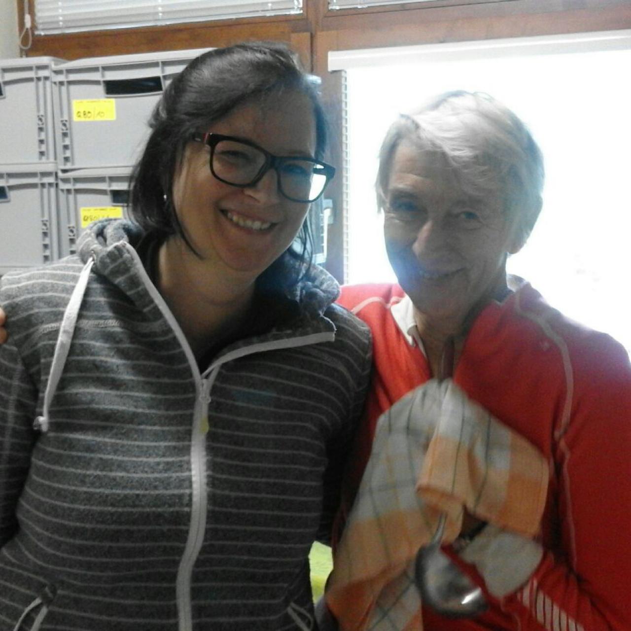 Bärbel und Heike umarmen sich vor einem Fenster und grauen Kisten