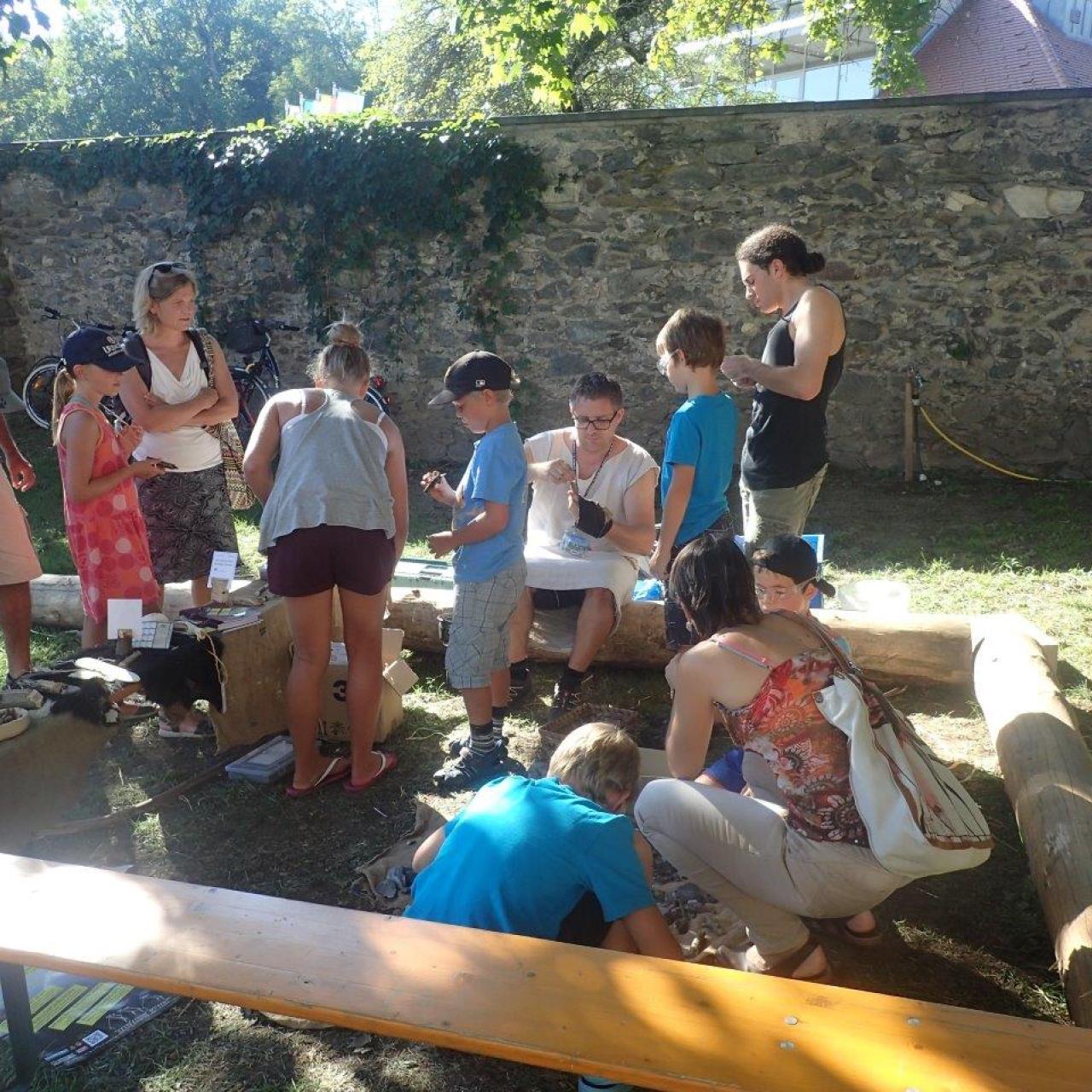 Eine Kindergruppe beim Welterbefest in Keutschach vor einer Mauer, bei einer Mitmachstation