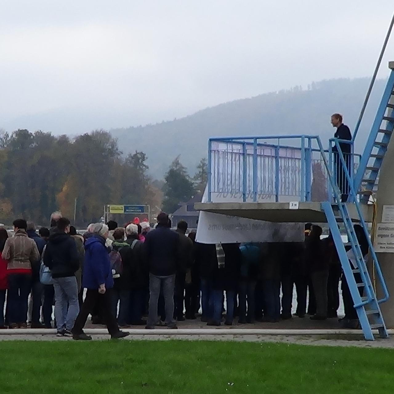 Eine große Menschengruppe drängt sich um den Sprungturm in Seewalchen